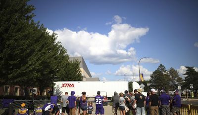 In this Monday, Aug. 8, 2017 photo, Minnesota Vikings fans watch as the football gear was being loaded on a truck at Minnesota State University, in Mankato, Minn. (Jerry Holt/Star Tribune via AP)