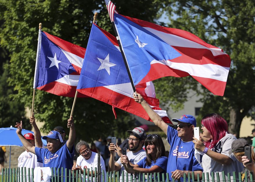Fans wave flags of Puerto Rico as compatriot Ivan Rodriguez speaks during his induction into the National Baseball Hall of Fame in Cooperstown, N.Y., Sunday, July 30, 2017. (AP Photo/Reed Saxon)