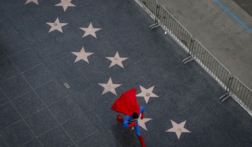 In this Thursday, March 2, 2017 photo, wearing a Superman costume, Toly Shtapenko, of Ukraine, takes a long stride along the Hollywood Walk of Fame to impress tourists, in the Hollywood section of Los Angeles. While the Hollywood we see in movies is a place of glamour and beautiful celebrities, the cast of superheroes filling Hollywood Boulevard is frequently anything but. Many are people struggling to make a buck as they pursue their dream of stardom. (AP Photo/Jae C. Hong)
