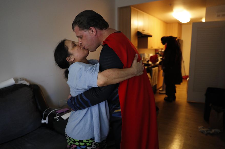 In this Tuesday, May 16, 2017 photo, wearing a Superman costume, Justin Harrison kisses his wife, Hope, in their apartment before heading out to Hollywood Boulevard in downtown Los Angeles. Harrison said they rely on help from the government to pay their rent because his income as a superhero impersonator isn't enough. (AP Photo/Jae C. Hong)
