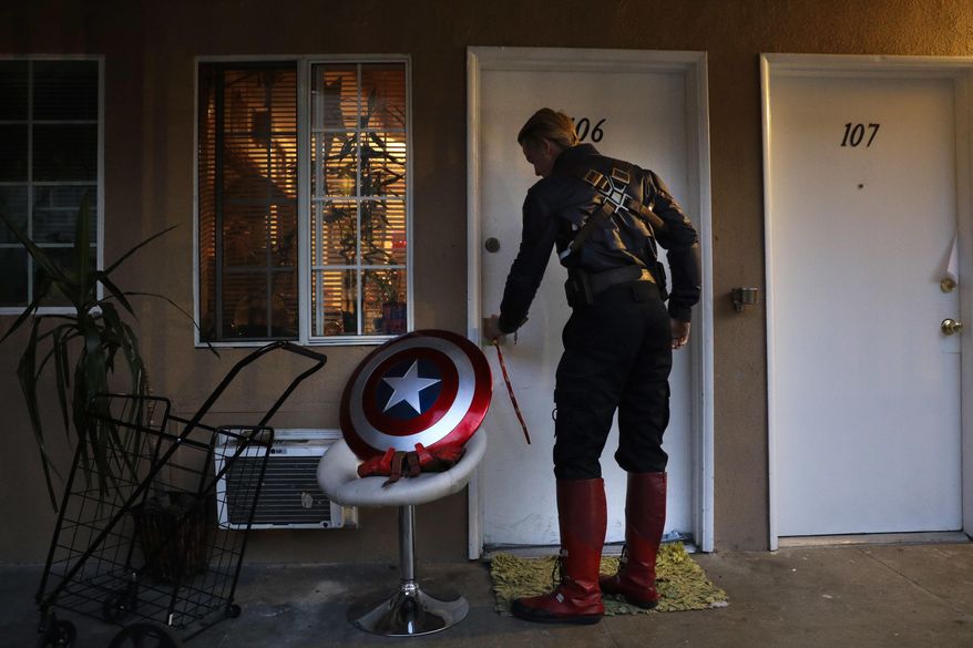 In this Monday, May 8, 2017 photo, Captain America impersonator Henry Hodge, a cinematographer from England who lives a stone's throw away from Hollywood's Dolby Theatre, opens his apartment door in Los Angeles. "The boulevard is the only thing that gives me the freedom to do what I really want to do," said Hodge. "I never have to miss a film meeting. I'm always available to shoot." (AP Photo/Jae C. Hong)