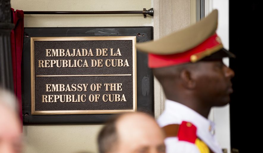 In this July 20, 2015, file photo, a member of the Cuban honor guard stands next to a new plaque at the front door of the newly reopened Cuban Embassy in Washington. The State Department has expelled two diplomats from Cuba’s Embassy in Washington following a series of unexplained incidents in Cuba that left U.S. officials there with physical symptoms. (AP Photo/Andrew Harnik, File, Pool)