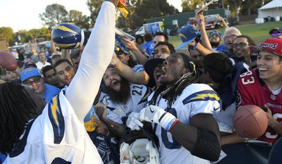 Los Angeles Chargers defensive end Melvin Ingram, left, pours candy over fans and running back Melvin Gordon during a joint NFL football practice with the Los Angeles Rams, Wednesday, Aug. 9, 2017, in Irvine, Calif. (AP Photo/Mark J. Terrill)