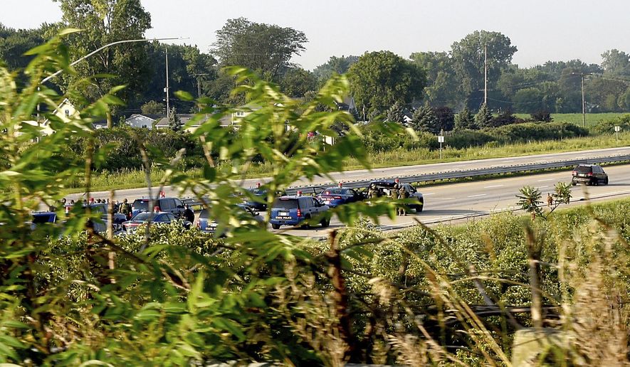 Troopers from the Michigan State Police, Monroe Post, negotiate with a man who had a gun after stopping the man on southbound Interstate 75 after he lead police on a chase that started in Pontiac and ended up on the highway in Erie Township, Mich., Thursday, Aug. 10, 2017. (Tom Hawley/The Monroe News via AP)