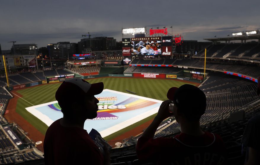 Daniel Baker, left, and Taylor Triggs, of Arlington, Va., wait under the concourse during a rain delay of a baseball game between the San Francisco Giants and the Washington Nationals, Friday, Aug. 11, 2017, in Washington. (AP Photo/Carolyn Kaster)