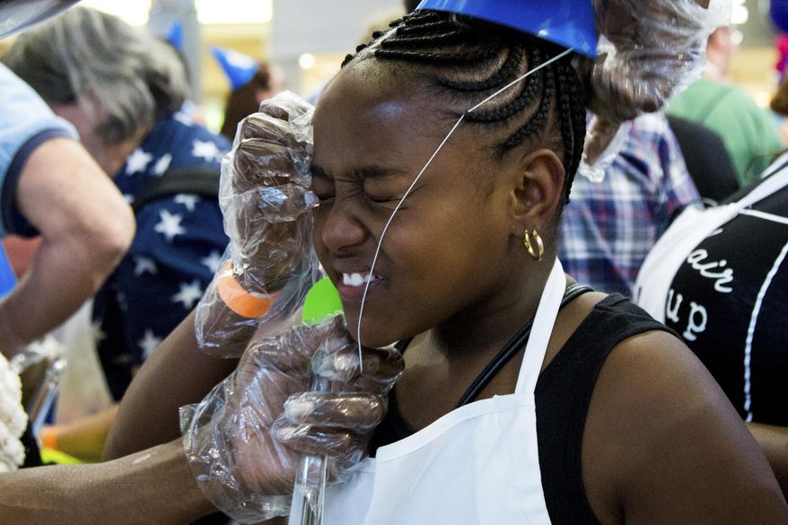 Kyla Davenport, 11, winces while her father puts her birthday conical hat back on during Mall of America's 25th birthday celebration, Friday, Aug. 11, 2017, in Bloomington, Minn. (Courtney Pedroza /Star Tribune via AP)