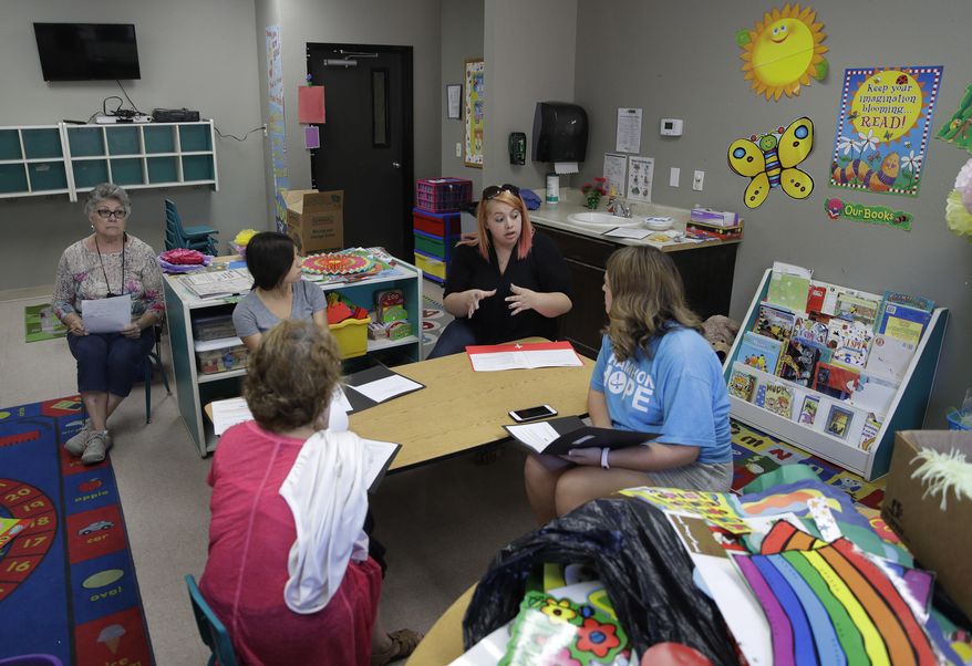 In this photo taken Aug. 8, 2017, Kelsey Nellis, second from right, instructs employees in preparation for the start of the school year at the Mountain View Christian Schools in Las Vegas. More than a third of U.S. states have created school voucher programs that bypass thorny constitutional and political issues by turning them over to non-profits that rely primarily on businesses to fund them. But the programs are raising questions about transparency and accountability at a time when supporters are urging that it be expanded into a federal program. (AP Photo/John Locher)