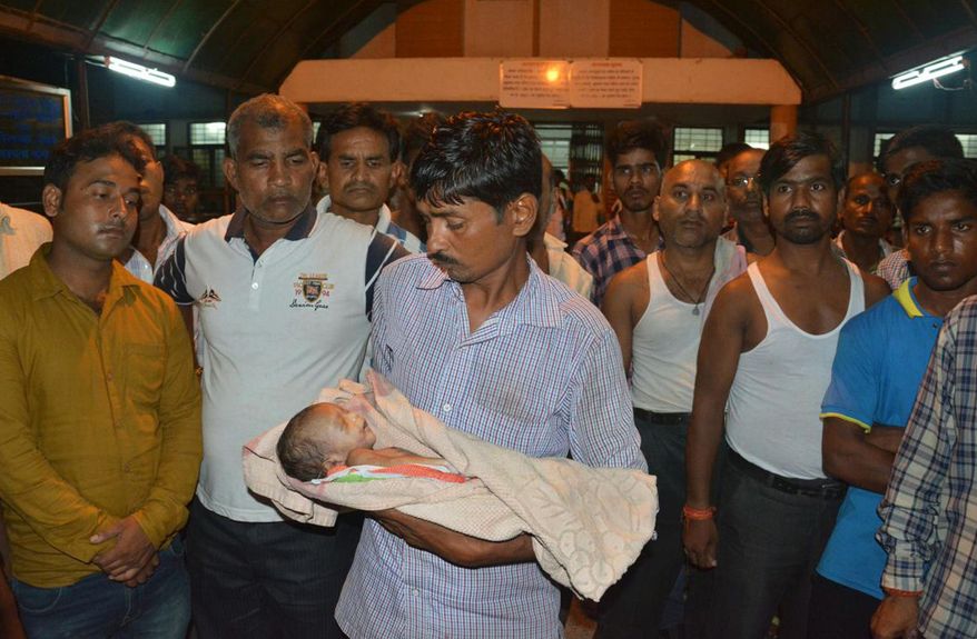 In this Friday, Aug. 11, 2017 photo, a man holds the lifeless body of his child outside Baba Raghav Das Medical College Hospital in Gorakhpur, in the northern Indian state of Uttar Pradesh. Parents of at least 35 children who have died in the hospital over the past three days have alleged that the fatalities were due to the lack of oxygen supply in the children's ward. District Magistrate Rajiv Rautela said Saturday the deaths of the children being treated for different ailments were due to natural causes. He denied that the lack of oxygen led to their deaths. (AP Photo)