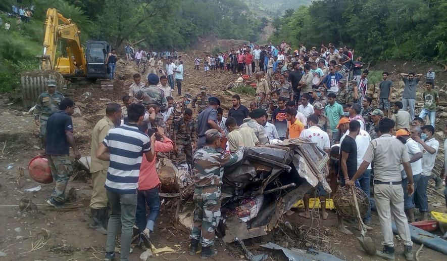 Army soldiers and rescue workers search for bodies of landslide victims even as they try to pull out two buses that were covered in mud after a landslide triggered by heavy monsoon rain in Urla village, Himachal Pradesh state, India, Sunday, Aug. 13, 2017. The landslide that occurred early Sunday buried part of a highway, trapping two buses and at least three cars. (AP Photo/Shailesh Bhatnagar)