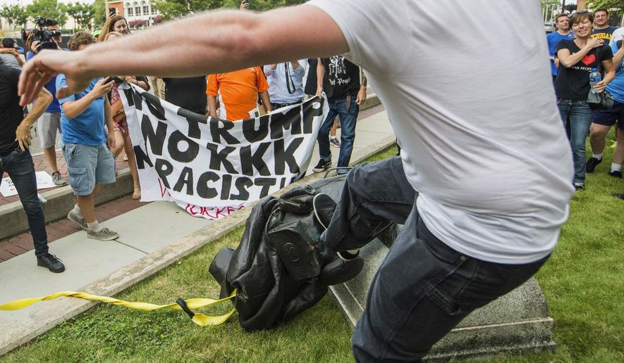 A protester kicks the toppled statue of a Confederate soldier after it was pulled down in Durham, N.C. Monday, Aug. 14, 2017. Activists on Monday evening used a rope to pull down the monument outside a Durham courthouse. The Durham protest was in response to a white nationalist rally held in Charlottesville, Va., over the weekend. (Casey Toth/The Herald-Sun via AP)