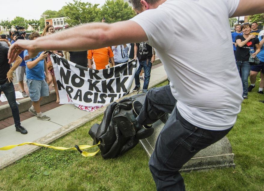 A protester kicks the toppled statue of a Confederate soldier after it was pulled down in Durham, N.C. Monday, Aug. 14, 2017. Activists on Monday evening used a rope to pull down the monument outside a Durham courthouse. The Durham protest was in response to a white nationalist rally held in Charlottesville, Va., over the weekend. (Casey Toth/The Herald-Sun via AP)