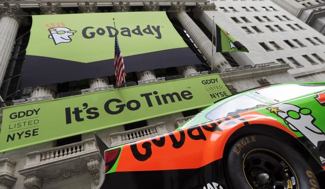 In this April 1, 2015, photo, GoDaddy signage and a race car announce the company&#x27;s IPO, in front of the New York Stock Exchange in New York. (AP Photo/Richard Drew) **FILE**