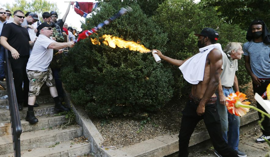 A counter demonstrator uses a lighted spray can against a white nationalist demonstrator at the entrance to Lee Park in Charlottesville, Va., Saturday, Aug. 12, 2017. (AP Photo/Steve Helber)