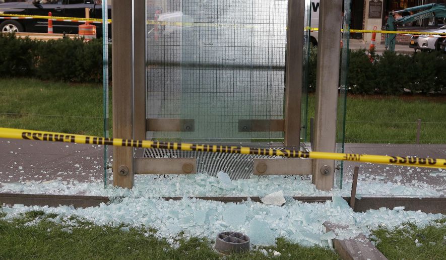 Broken glass lies on the ground near police tape at the New England Holocaust Memorial, Monday, Aug. 14, 2017, in Boston. Police say a person is in custody for allegedly vandalizing the memorial. It's the second time the memorial has been damaged this summer. (AP Photo/Steven Senne)