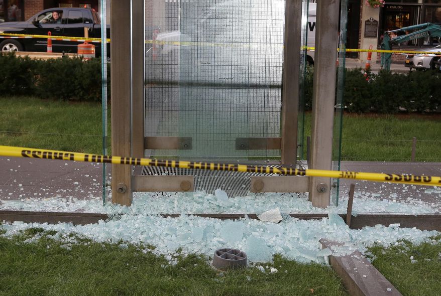 Broken glass lies on the ground near police tape at the New England Holocaust Memorial, Monday, Aug. 14, 2017, in Boston. Police say a person is in custody for allegedly vandalizing the memorial. It's the second time the memorial has been damaged this summer. (AP Photo/Steven Senne)