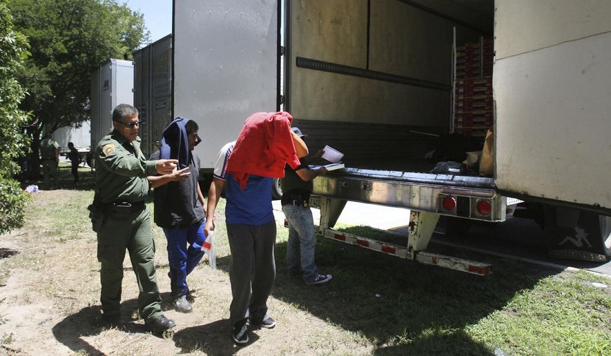 In this Sunday Aug. 13, 2017, file photo, Border Patrol officers escort a group of immigrants to a van after a group was found in the tractor-trailer in Edinburg, Texas. Police in Texas acting on a tip found the immigrants locked inside the tractor-trailer parked at a gas station about 20 miles (30 kilometers) from the border with Mexico, less than a month after 10 people died in the back of a hot truck with little ventilation in San Antonio. (Delcia Lopez/The Monitor via AP)