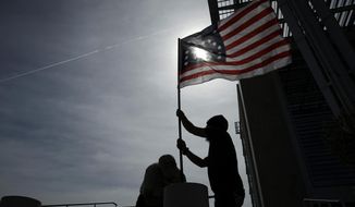 FILE - In this April 24, 2017, file photo, supporters raise a flag outside of the federal courthouse in Las Vegas. A retrial is nearing an end in Nevada for four men facing decades in prison for bringing assault-style weapons to a confrontation that stopped government agents from rounding up cattle near anti-government figure Cliven Bundy&#39;s ranch in April 2014. (AP Photo/John Locher, File)
