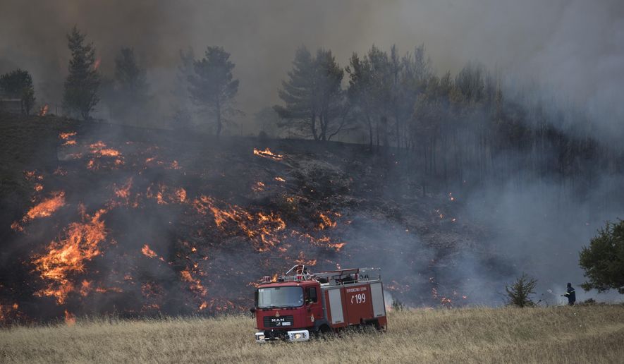 A firefighters sprays water during a forest fire in the village of Metohi north of Athens, on Monday, Aug. 14, 2017. A large wildfire north of Athens is threatening homes as it sweeps through pine forest for a second day, uncontained due to high winds.(AP Photo/Petros Giannakouris)