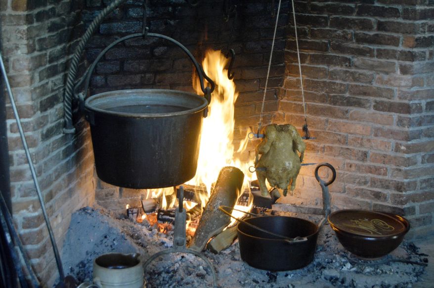 In this June 10, 2017 photo provided by Tracee Herbaugh, mustard greens cook in a cast iron pot hanging over a fire at Old Sturbridge Village in Sturbridge, Mass. In the 19th century, most meals had to be cooked over the home's central hearth. (Tracee Herbaugh via AP)