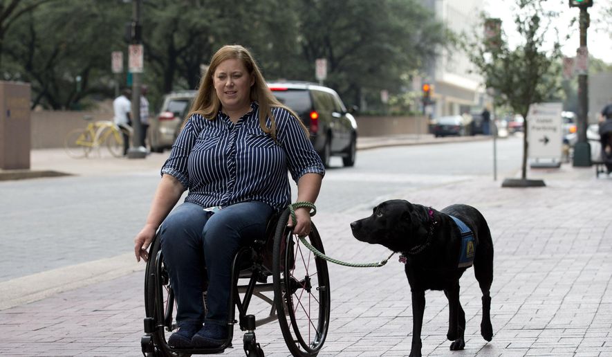 In this file photo, Susan Mahoney, who lives in downtown Dallas, takes her service dog Misha out for a walk on Thursday, August 3, 2017. She received her service dog Misha III from Canine Companions for Independence, who work with female inmates at the Federal Medical Center Carswell to train puppies to be service dogs. On Sept. 1, 2019, a new law takes effect in Alabama that penalizes individuals who misidentify their pet as a service animal if the animal in question is not legitimately trained for such a purpose. (Joyce Marshall/Star-Telegram via AP) **FILE**