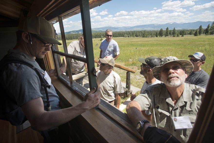 This photo taken July 12, 2017, shows Kevin Brothers, left, and Tom Lincoln removing a window from one of the guest cabins at the White Grass Dude Ranch in Grand Teton National Park as part of a window and door restoration workshop. The ranch has become the headquarters for the Western Center for Historic Preservation, where participants come from national parks around the country and learn restoration and preservation skills to take back to their respective park or monument. (Bradly J. Boner /Jackson Hole News & Guide via AP)