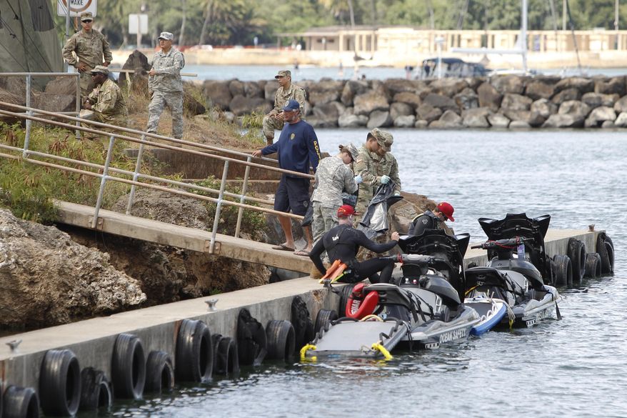 Honolulu ocean safety lifeguards on jet skis hand over materials to military personnel stationed at a command center at a boat harbor, Wednesday, Aug. 16, 2017, in Haleiwa, Hawaii. An Army helicopter with five on board crashed several miles off Oahu's North Shore late Tuesday. (AP Photo/Marco Garcia)