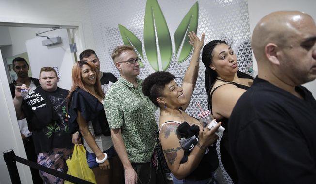 FILE- In this July 1, 2017 file photo, people wait in line at the Essence cannabis dispensary in Las Vegas. A judge cleared the way Thursday, July 17, for Nevada to allow more businesses to move marijuana from growers to stores in an effort to keep up with overwhelming demand since recreational pot sales began last month. (AP Photo/John Locher, File)