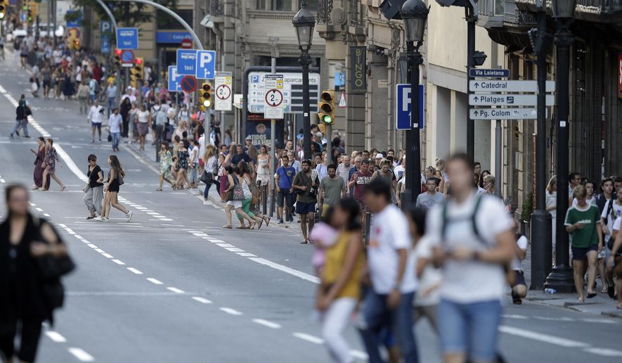 People walk down a main street in Barcelona, Spain, Thursday, Aug. 17, 2017. Police in Barcelona say a white van has mounted a sidewalk, struck several people in the city&#x27;s Las Ramblas district. (AP Photo/Manu Fernandez)