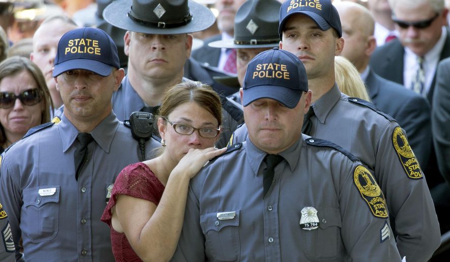 Susanne Kain, center left, comforts her husband, Virginia State Police Sgt. CM Kain, center right, during the funeral of Virginia State Trooper-Pilot Berke Bates at St. Paul's Baptist Church in Richmond, Va., on Friday, Aug. 18, 2017. Bates died in a fatal crash of a helicopter that had been monitoring a violent white-nationalist protest in Charlottesville, Va. (Daniel Sangjib Min/Richmond Times-Dispatch via AP)