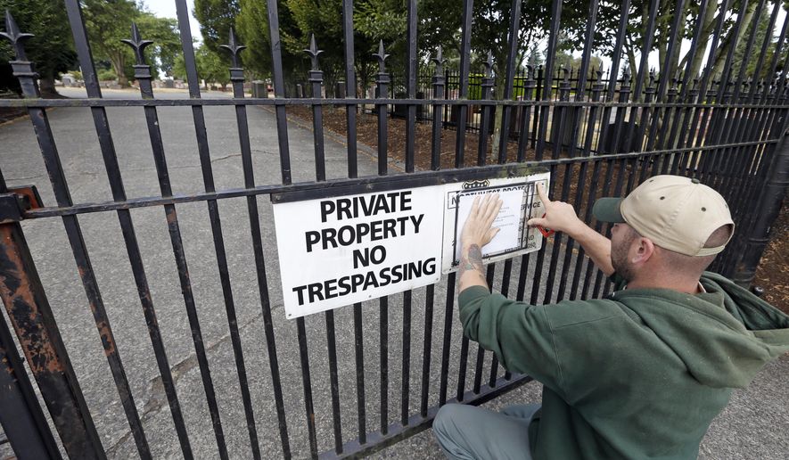 A worker, who declined to be identified, posts a notice of temporary closure on the locked gates of Lake View Cemetery, which was shut following angry messages they've received over a memorial for Confederate soldiers, Thursday, Aug. 17, 2017, in Seattle. The private cemetery was shut down a day earlier and is expected to remain closed through the weekend over a memorial that's stood there nearly a century and now there's a petition asking for it to come down. The memorial was built with help from the Daughters of the Confederacy 91 years ago. (AP Photo/Elaine Thompson)