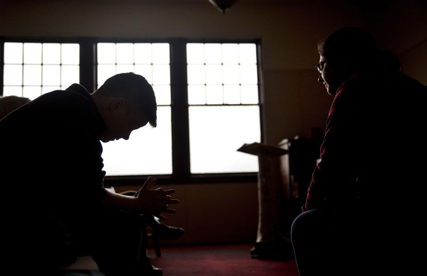 Aaron Scott, left, prays during a service conducted by Rev. Sarah Monroe, right, at Chaplains on the Harbor church in Westport, Wash., Thursday, June 15, 2017. "I don't think our politicians know how high the stakes are here, and after so many years have gone by with our situation still as devastated as it is, I don't know if they care," Monroe says. "I'm not sure how much worse it can get, and at the same time I'm afraid to see how much worse it can get." (AP Photo/David Goldman)