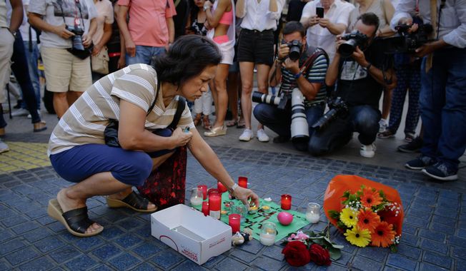 A woman places a candle on a paper that reads &amp;quot;Catalunya - place of peace&amp;quot; in Las Ramblas, Barcelona, Spain, Friday, Aug. 18, 2017. Spanish police on Friday shot and killed five people carrying bomb belts who were connected to the Barcelona van attack that killed at least 13, as the manhunt intensified for the perpetrators of Europe&#x27;s latest rampage claimed by the Islamic State group. (AP Photo/Manu Fernandez)
