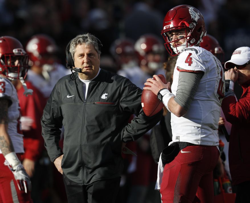 FILE - In this Nov. 19, 2016, file photo, Washington State head coach Mike Leach, left, confers with quarterback Luke Falk during an injury time out against Colorado in the first half of an NCAA college football game in Boulder, Colo. As college football season approaches teams all over the country are choosing captains, those hard-working, high-character players who set an example for their teammates to follow through both actions and words. (AP Photo/David Zalubowski, File)