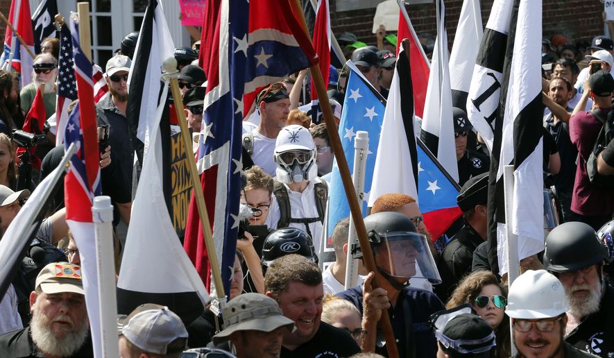 In this Saturday, Aug. 12, 2017 file photo, white nationalist demonstrators walk into the entrance of Lee Park surrounded by counter demonstrators in Charlottesville, Va. (AP Photo/Steve Helber)