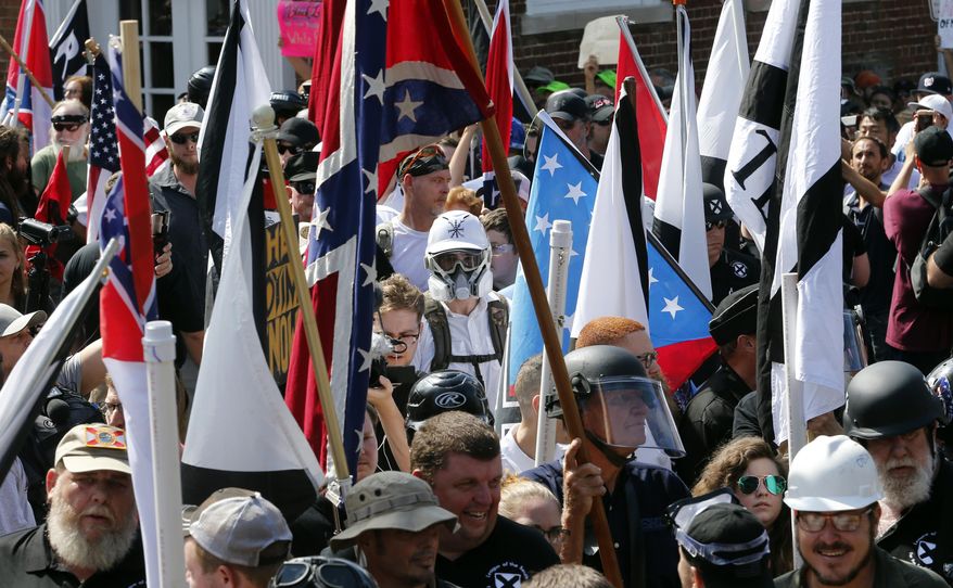 In this Saturday, Aug. 12, 2017 file photo, white nationalist demonstrators walk into the entrance of Lee Park surrounded by counter demonstrators in Charlottesville, Va. (AP Photo/Steve Helber)
