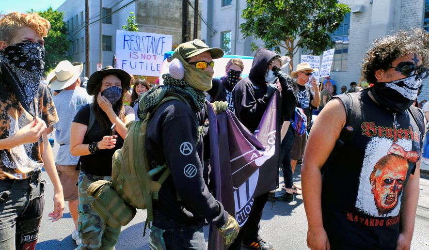 A masked group of demonstrators join in a protest against racism in the Venice beach area of Los Angeles on Saturday, Aug. 19, 2017. The peace and unity gathering was held Saturday morning at the beach south of Los Angeles in response to the deadly events at a white nationalist gathering in Charlottesville, Virginia. (AP Photo/Richard Vogel)