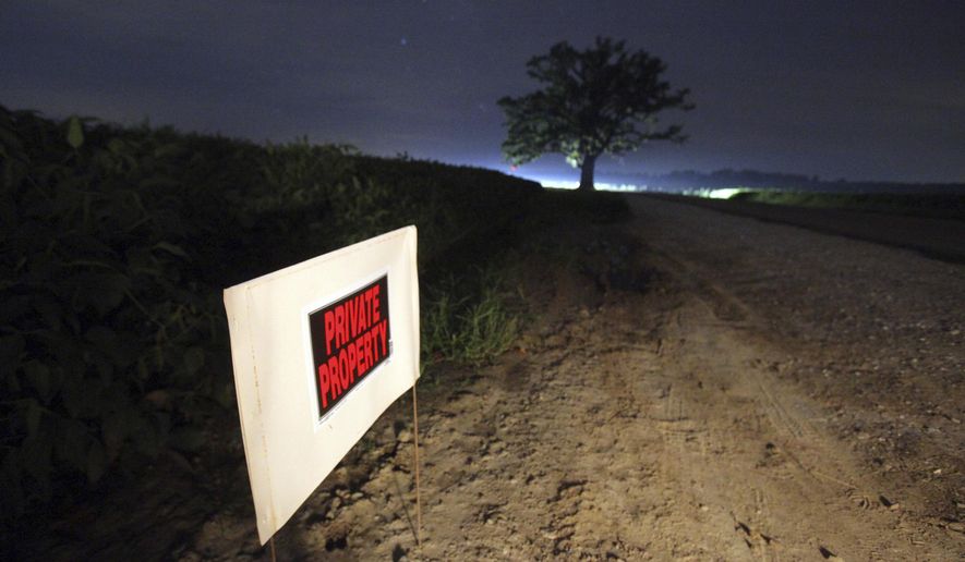 Signs warn visitors to the 350-year-old bur oak to stay on the shoulder of the road and not to venture into healthy soybean fields, outside Columbia, Mo., Sunday night, Aug. 20, 2017. Bur Oak Road, a narrow two-lane road that cuts through Missouri River bottomland, runs near the tree and is a popular spot for locals to take in nighttime spectacles. The area is expected to be a popular spot for watching Monday&#x27;s solar eclipse. (Brian Kratzer/Missourian via AP)