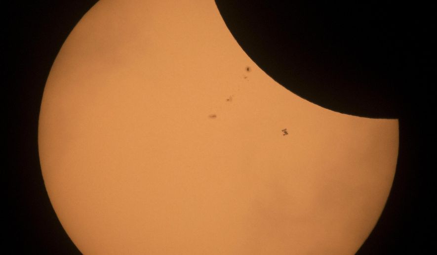 The International Space Station is seen in silhouette as it transits the sun during a partial solar eclipse, Monday, Aug. 21, 2017, near Banner, Wyo. (Joel Kowsky/NASA via AP)