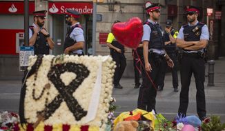 Police officers stand guard next to flags, flowers, messages and candles to the victims on Barcelona&#39;s historic Las Ramblas promenade on the Joan Miro mosaic, embedded in the pavement where the van stopped after killing at least 14 people in Barcelona, Spain, Monday, Aug. 21, 2017. (AP Photo/Emilio Morenatti)