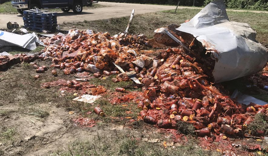 In this Monday, Aug. 21, 2017, photo provided by the Camden News, broken jars of spaghetti sauce litter a road near Camden, Ark. The crash marked the third time this month that edible goods were left on an Arkansas highway. A tanker spilled bourbon on Interstate 40 in eastern Arkansas on Aug. 2, and on Aug. 9 a truck split open on Interstate 30 in Little Rock, spilling frozen pizza. (Shantelle Laughlin/Camden News via AP)