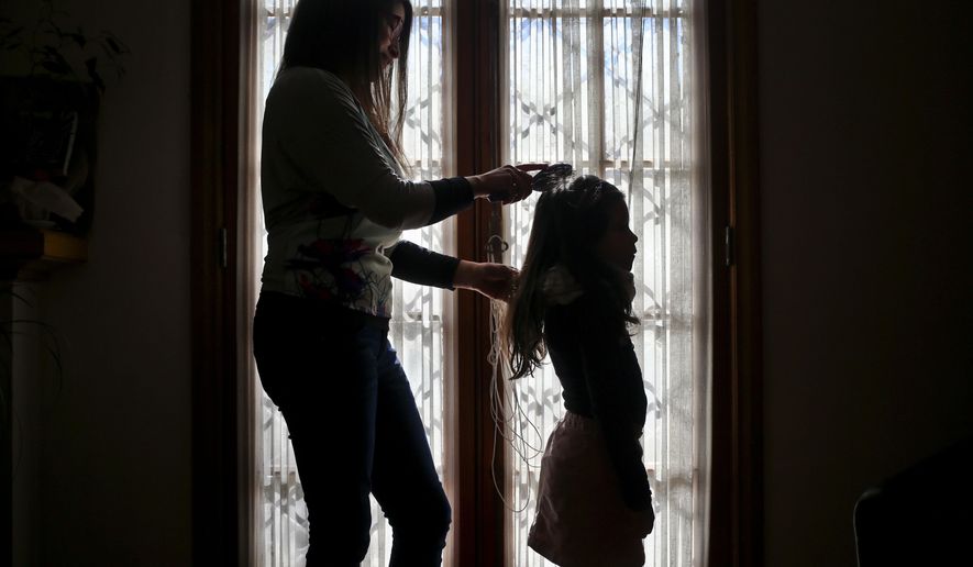 In this July 18, 2017 photo, Monica Flores combs her daughter's hair at their home in Santiago, Chile. Flores was questioned by Chilean police at the airport because the records didn't match: she had left on holidays abroad with a son and returned to the country with a daughter who went by the name Luna. In front of airport authorities, she had to explain that her 6-year-old registered as a boy identified as a girl. (AP Photo/Esteban Felix)