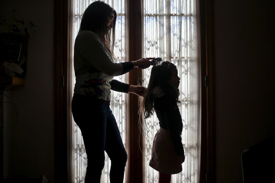 In this July 18, 2017 photo, Monica Flores combs her daughter's hair at their home in Santiago, Chile. Flores was questioned by Chilean police at the airport because the records didn't match: she had left on holidays abroad with a son and returned to the country with a daughter who went by the name Luna. In front of airport authorities, she had to explain that her 6-year-old registered as a boy identified as a girl. (AP Photo/Esteban Felix)