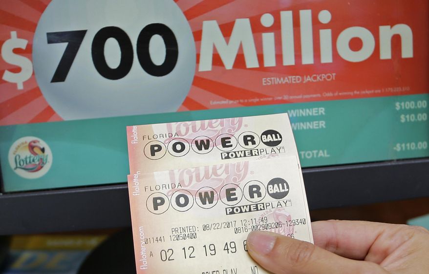 A customer shows her purchased Powerball tickets for Wednesday's drawing, Tuesday, Aug. 22, 2017, in Hialeah, Fla. The winner could take the $700 million annuity option (paid out over 29 years) or the $443.3 million cash prize, minus state and federal taxes. (AP Photo/Alan Diaz)