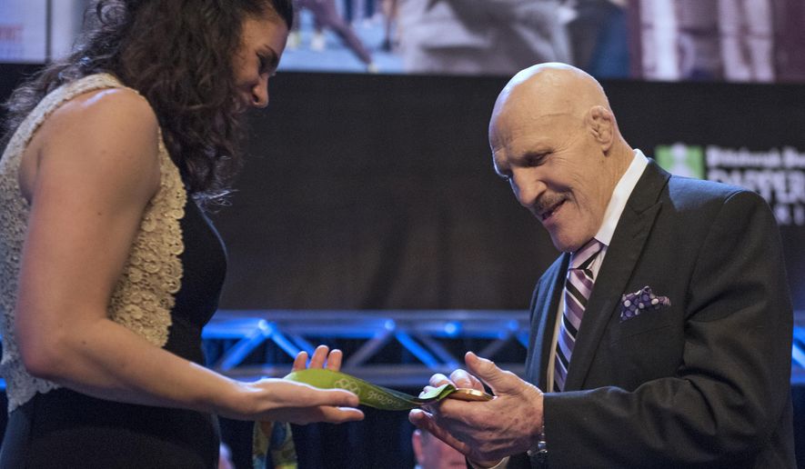 FILE – In this Feb. 15, 2017, file photo, retired professional wrestler Bruno Sammartino examines U.S. rower Amanda Polk&#39;s Olympic gold medal at the 81st Dapper Dan Awards and sports auction, a fundraiser for the Boys &amp;amp; Girls Clubs of Western Pennsylvania, in Pittsburgh. Sammartino met with pop singing sensation Bruno Mars on Tuesday, Aug. 22, 2017, when Mars&#39; 24K Magic World Tour stopped in Pittsburgh, after Sammartino heard Mars was nicknamed &amp;quot;Bruno&amp;quot; as a baby because Sammartino was Mars&#39; father&#39;s favorite wrestler. (Haley Nelson/Pittsburgh Post-Gazette via AP, File)