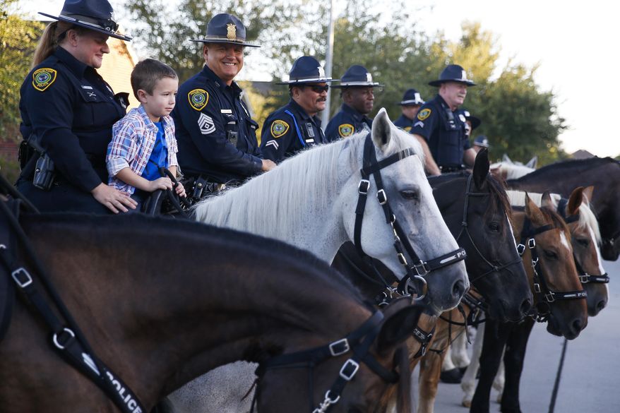 Kevin Will Jr., 5, the son of slain Houston police officer Kevin Will, sits on top of a horse as he is escorted to his first day of school by Houston police and other officers Tuesday, Aug. 22, 2017 in Cypress, Texas. Officer Kevin Will died in May 2011 after being hit by a vehicle at the scene of an unrelated wreck. His wife was pregnant at the time. (Michael Ciaglo/Houston Chronicle via AP)