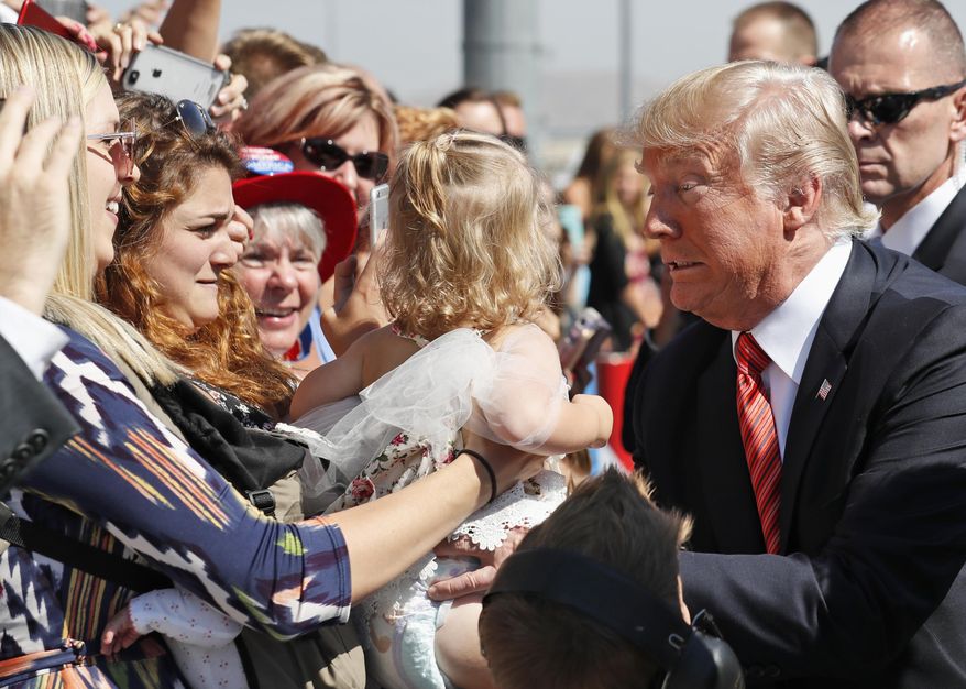 President Donald Trump struggles to hold a baby as he greets supporters as he arrives in Reno, Nev., Wednesday, Aug. 23, 2017. (AP Photo/Alex Brandon) ** FILE **