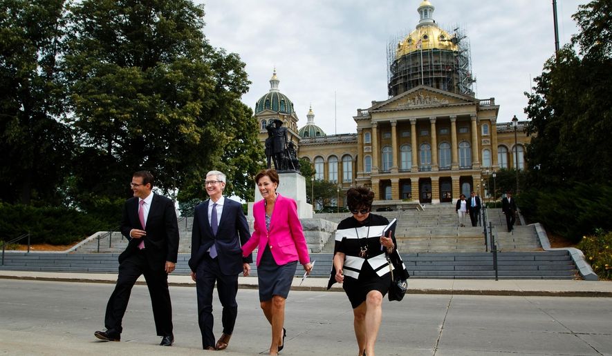 Apple CEO Tim Cook, second from left, and Iowa Gov. Kim Reynolds, third from left, walk to a podium in front of the Capitol building, background, in Des Moines, Iowa, Thursday, Aug. 24, 2017, to announce Apple's plans for two new data storage centers and to create at least 50 jobs near Des Moines. (Brian Powers/The Des Moines Register via AP)