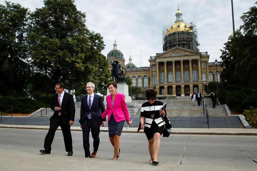 Apple CEO Tim Cook, second from left, and Iowa Gov. Kim Reynolds, third from left, walk to a podium in front of the Capitol building, background, in Des Moines, Iowa, Thursday, Aug. 24, 2017, to announce Apple's plans for two new data storage centers and to create at least 50 jobs near Des Moines. (Brian Powers/The Des Moines Register via AP)