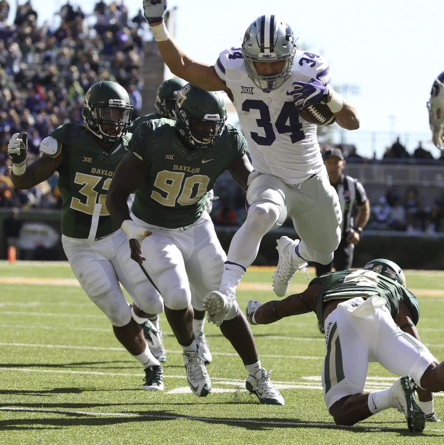 This photo taken Nov. 19, 2016, shows Kansas State running back Alex Barnes (34) scoring past Baylor cornerback Grayland Arnold, right, and defensive end Tyrone Hunt (90), in the second half of an NCAA college football game, in Waco, Texas. (Jerry Larson/Waco Tribune Herald via AP)