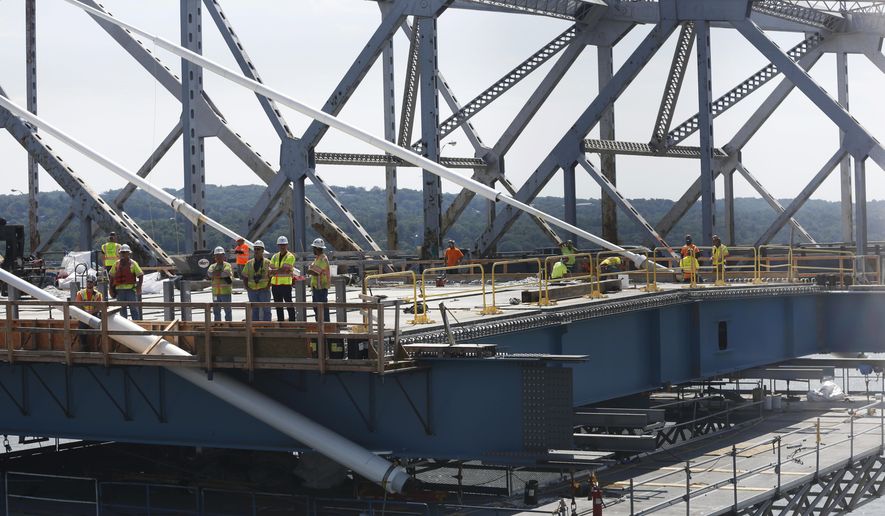 Construction workers watch a ribbon cutting ceremony from an uncompleted section of the Tappan Zee Bridge replacement, called the Gov. Mario M. Cuomo Bridge, near Tarrytown, N.Y., Thursday, Aug. 24, 2017. The event was held a day before vehicles start rolling across on side of the new Hudson River span. (AP Photo/Seth Wenig)